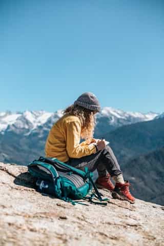 Girl writing in journal on mountain