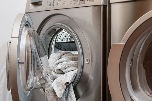 Open washing machine with towel hanging out
